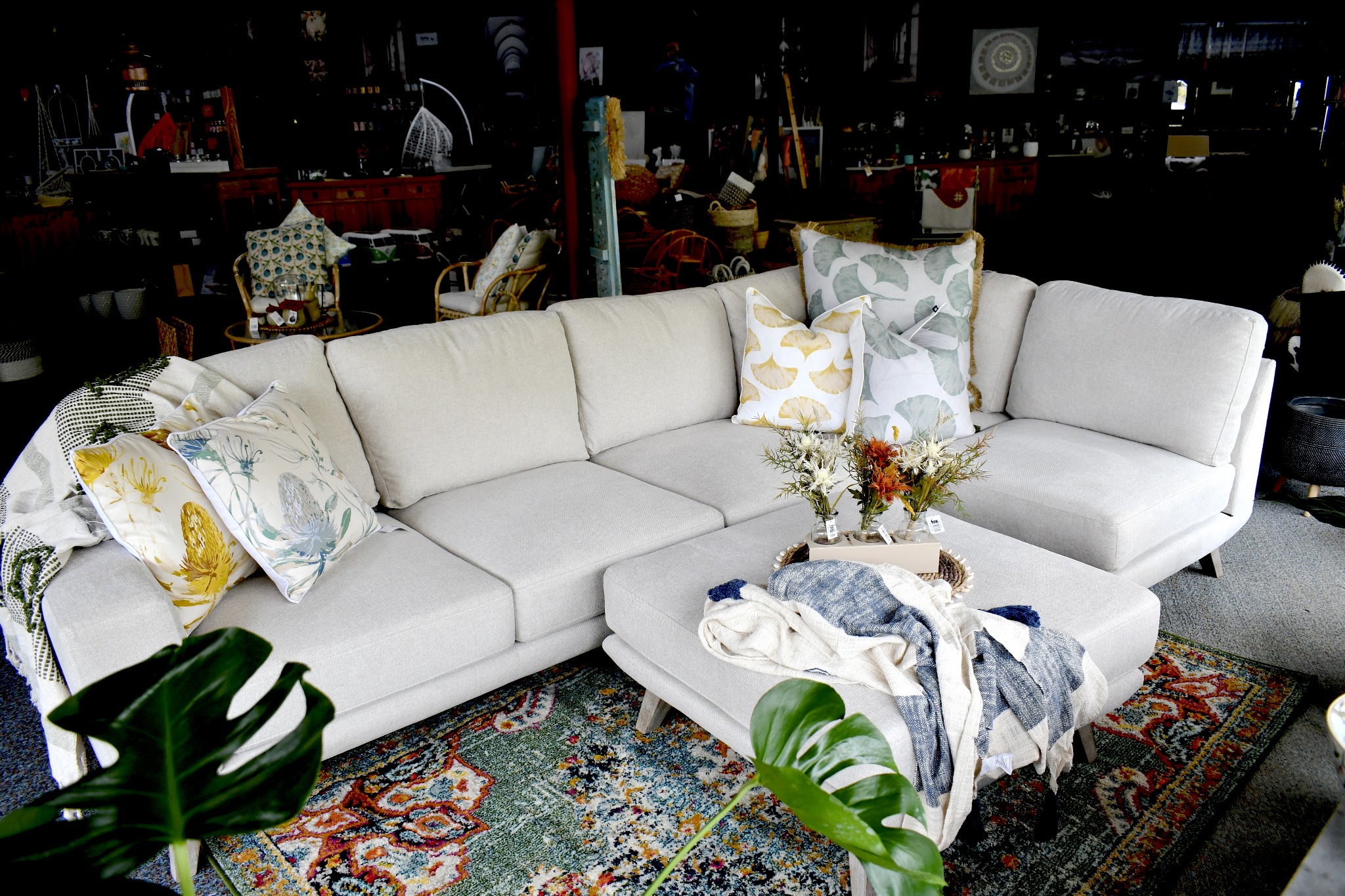 A linen modular sofa styled with botanical cushions, throws and a patterned rug inside the homewares showroom