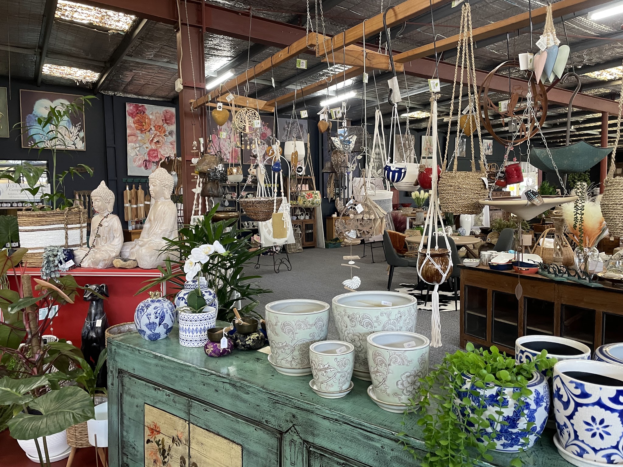 Hanging macrame planters, glazed pots, blue and white ceramics and floral canvases inside the giftware room