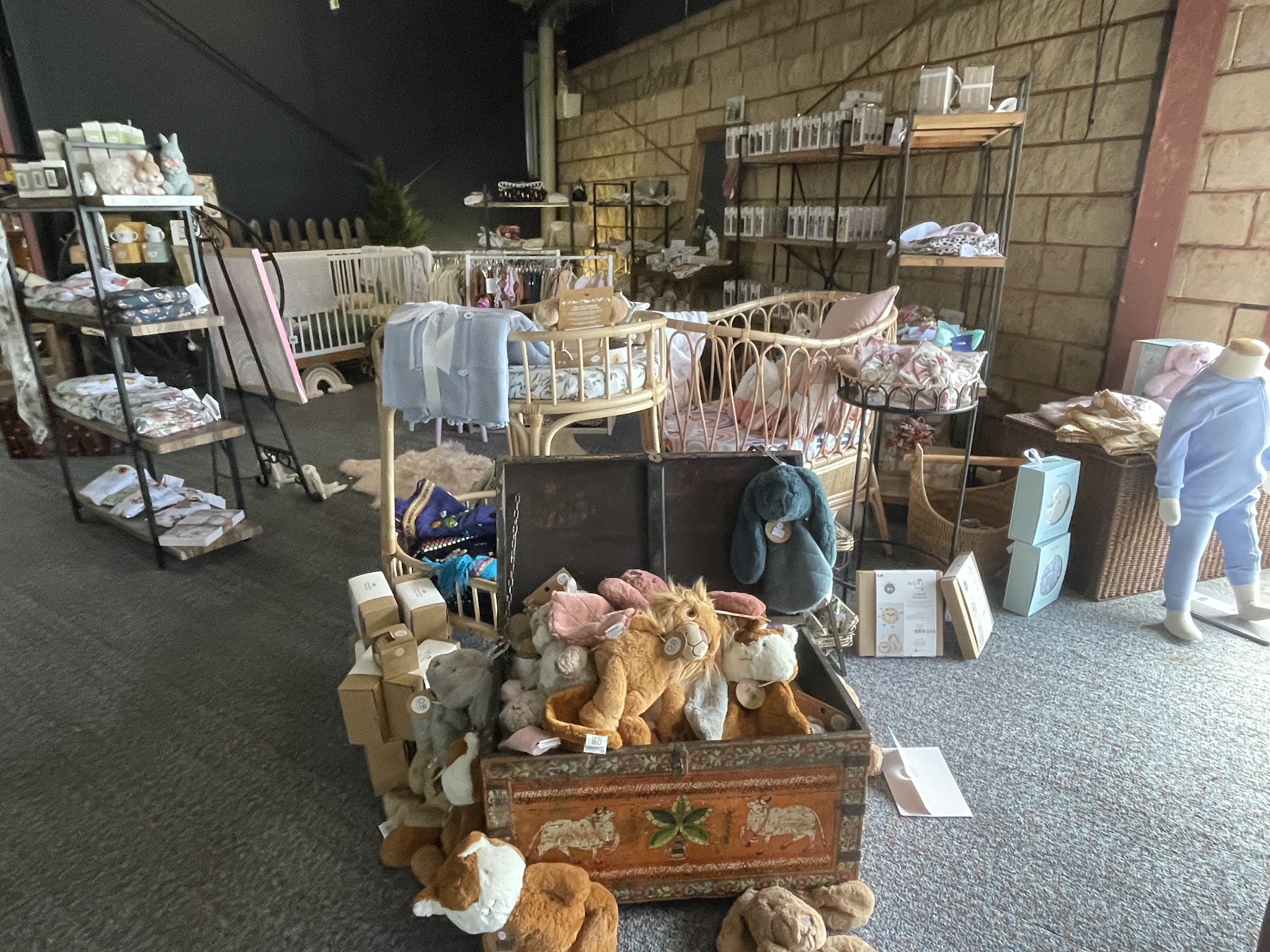 Rattan cots, soft toys in a painted chest and rails of baby clothing in the children's boutique